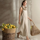 Woman in a beige dress holding a woven bag next to a basket of lemons.