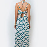 A model wearing a halter neck, sleeveless, maxi-length dress with a geometric pattern in teal and cream colors.