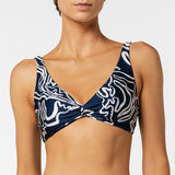 Navy blue bikini top with white abstract pattern worn by a model on a white background.
