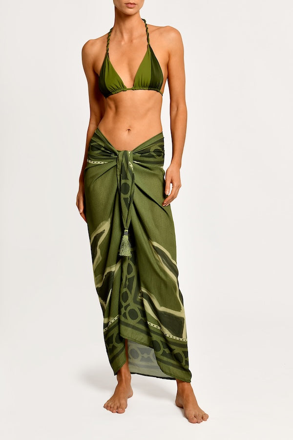 Woman wearing a green bikini with a matching sarong on a white background.