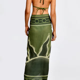 Women wearing green patterned bikini with matching sarong set on a white background.