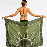 Woman holding a green sarong with a sun design on a white background.