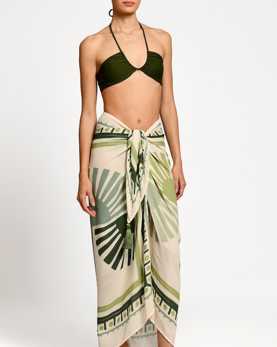 Woman wearing a green bikini with a matching leaf-patterned sarong on a white background.