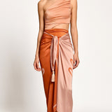 Woman wearing a peach and orange one-shoulder dress with a matching skirt on a white background.