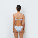 A person wearing a blue and white geometric patterned bikini bottom from the back.
