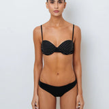 A model wearing a black bikini top with white stitching and matching full coverage bottoms.
