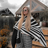 A woman wearing a black and white poncho inspired by geometric shapes in nature.