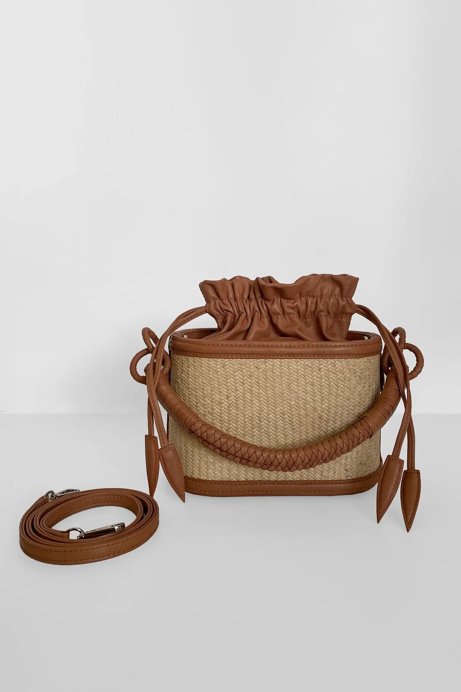 Brown woven bucket bag with leather accents on a white background.