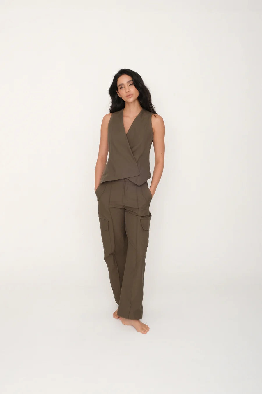 Woman wearing a brown sleeveless top and pants on a white background.