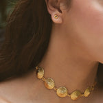 Close-up of a person wearing a gold necklace and earrings.