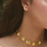 Close-up of a person wearing a gold necklace and earrings.