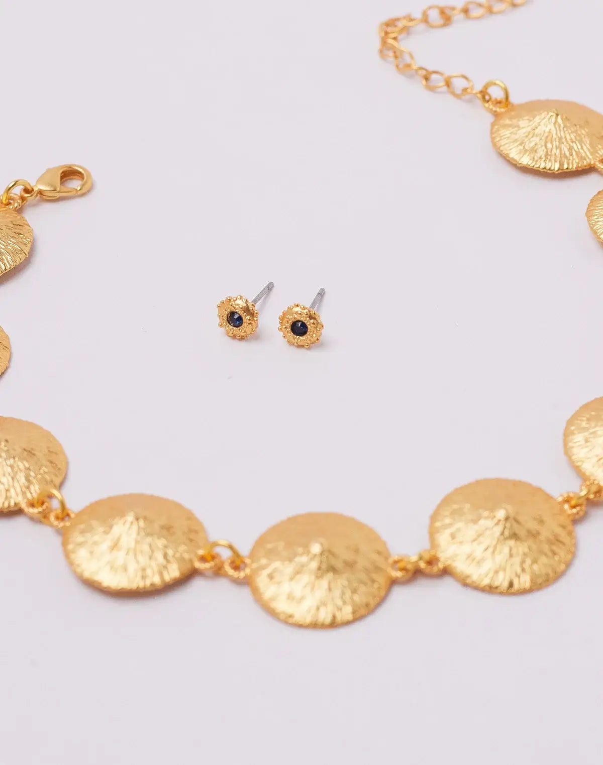 Gold necklace and earrings on a light gray background.