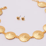 Gold necklace and earrings on a light gray background.
