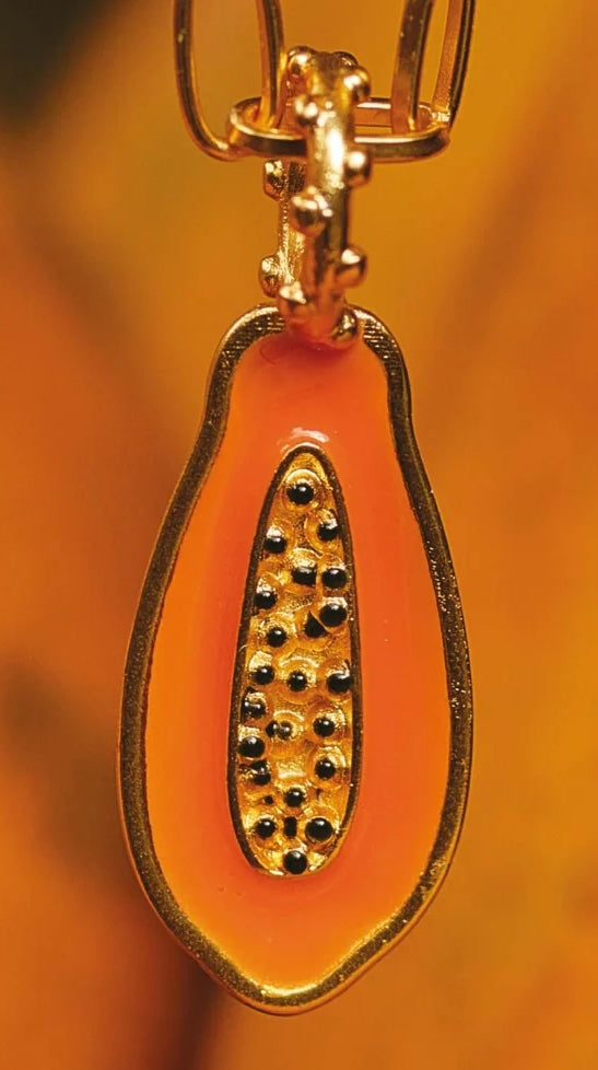 A close-up of a papaya gold-plated charm.
