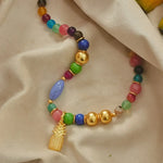 A gold-plated pineapple pendent necklace with oversized multicolored beads.
