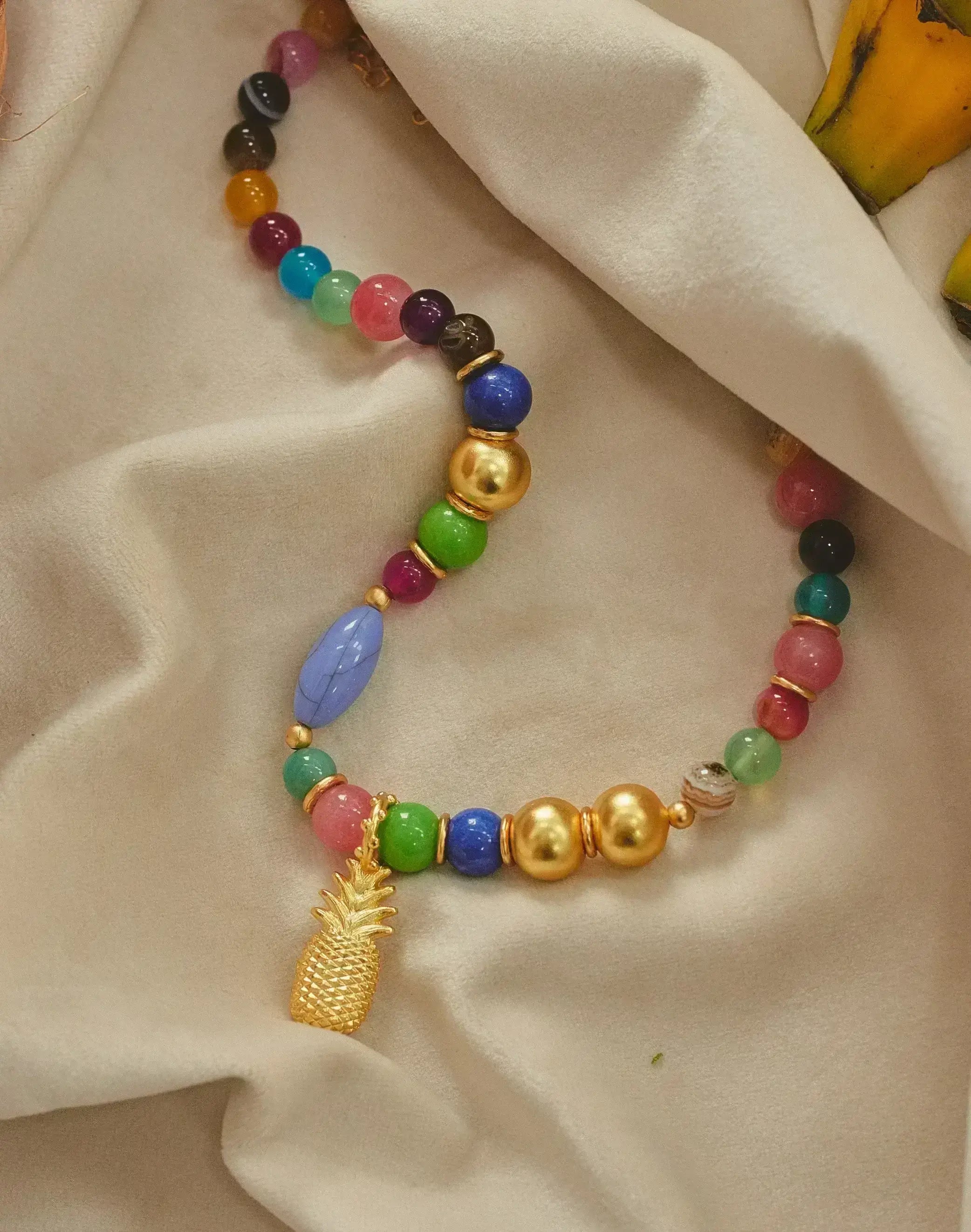 A gold-plated pineapple pendent necklace with oversized multicolored beads.
