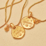 A collection of 24k gold-plated necklaces with different zodiac sign pendants, each accompanied by a natural stone charm, displayed on a beige background.