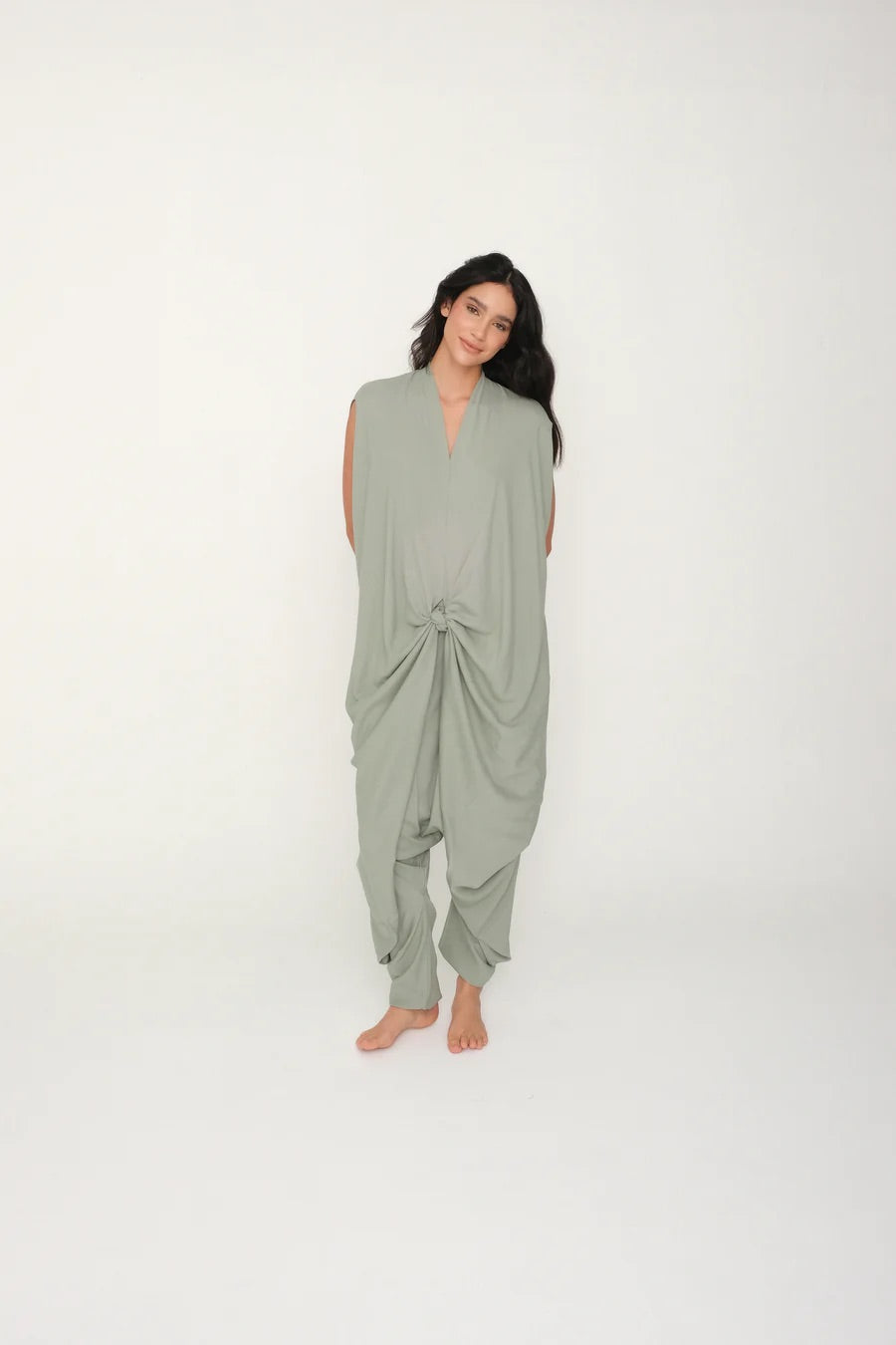 Woman wearing a green flowy jumpsuit on a white background.