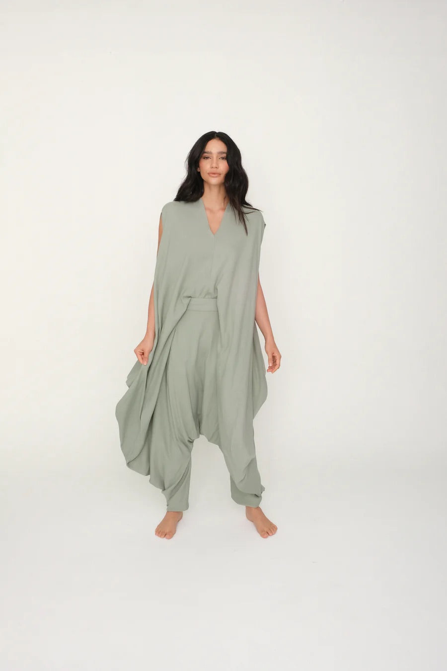 Woman wearing a green flowy jumpsuit against a white background.