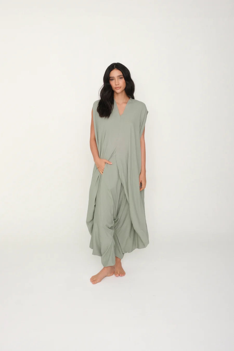 Woman wearing a light green jumpsuit on a white background.