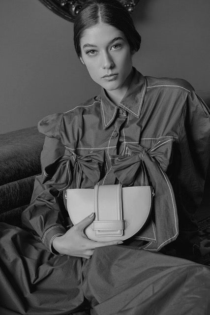 Person holding a handbag in a black and white setting.