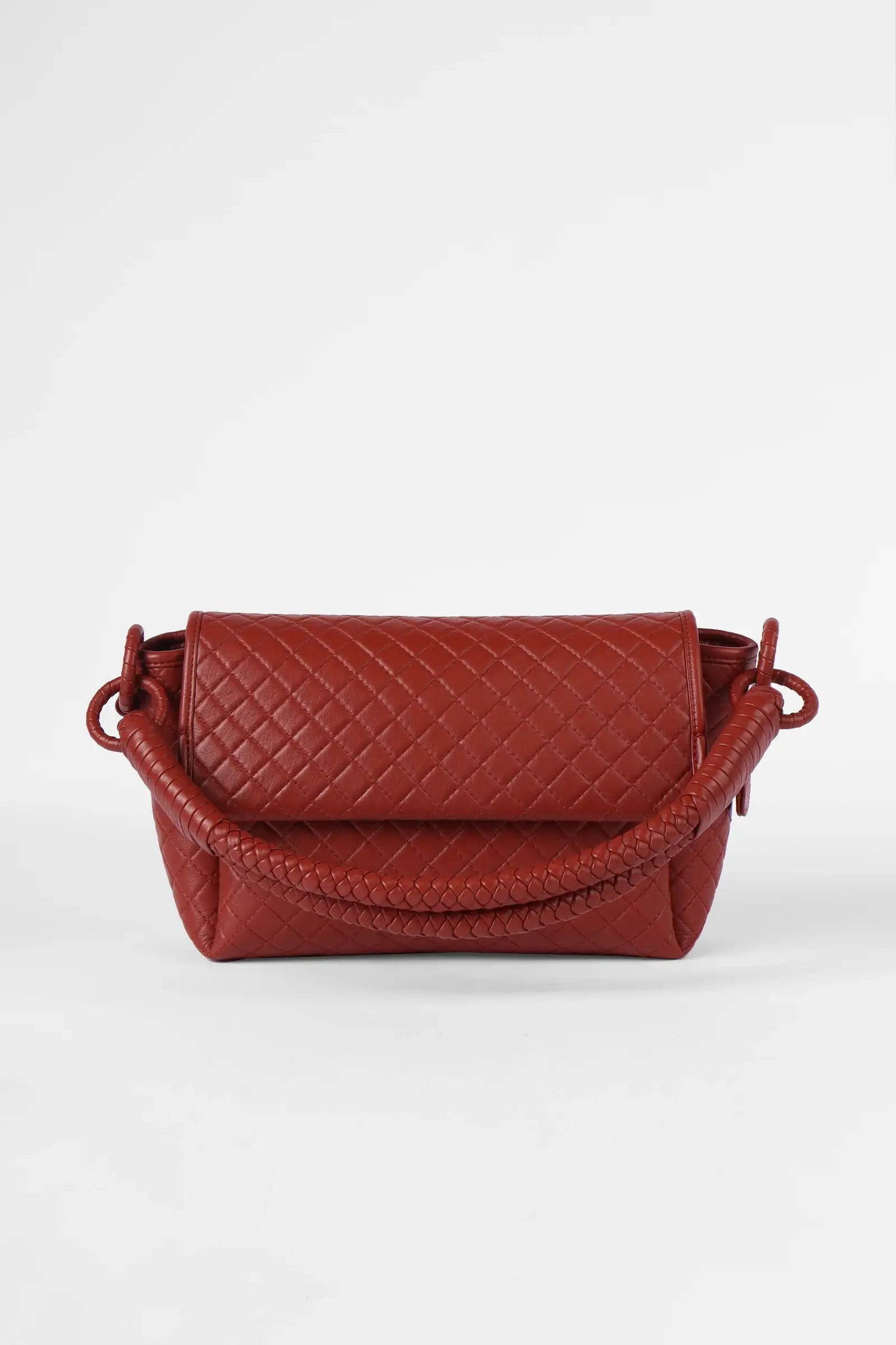 Red quilted handbag on a white background.