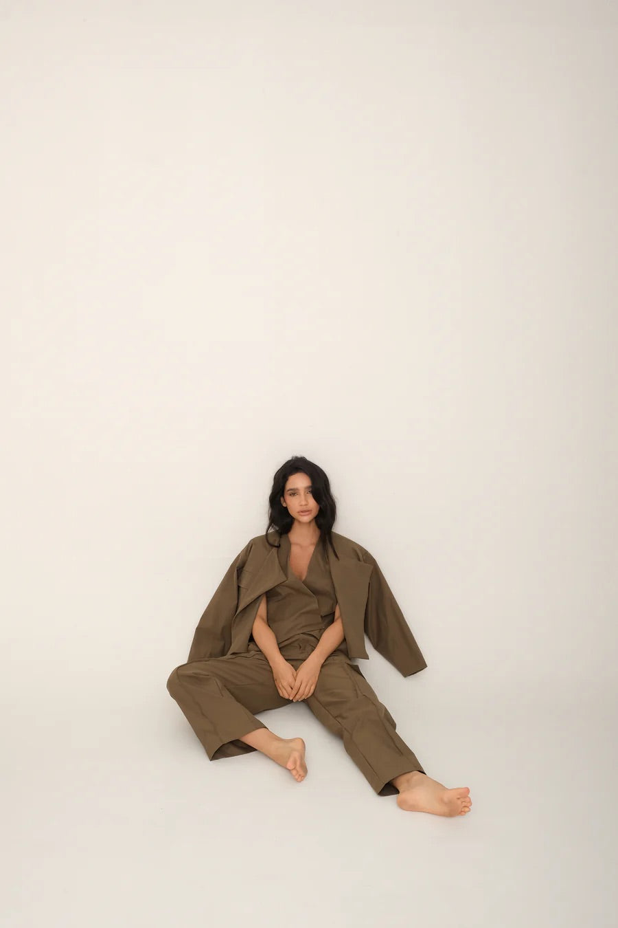 Person wearing a green outfit sitting on a white background.