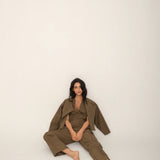 Person wearing a green outfit sitting on a white background.