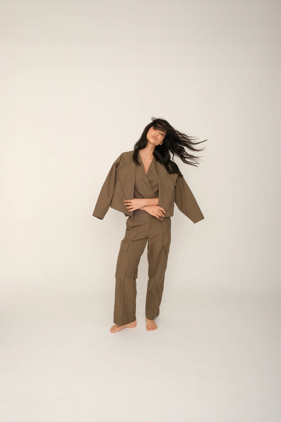 Woman wearing a brown top and pants set with a matching jacket on a white background.