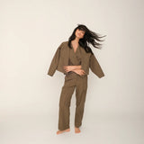 Woman wearing a brown top and pants set with a matching jacket on a white background.