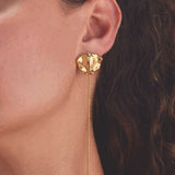 Close-up of gold sting ray earring worn by a person with dark hair.