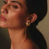 Close-up of a woman wearing a gold sting-ray earring with a dark background.