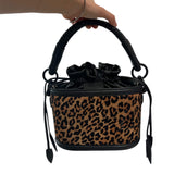Leopard print handbag with black handle and strap on a white background.