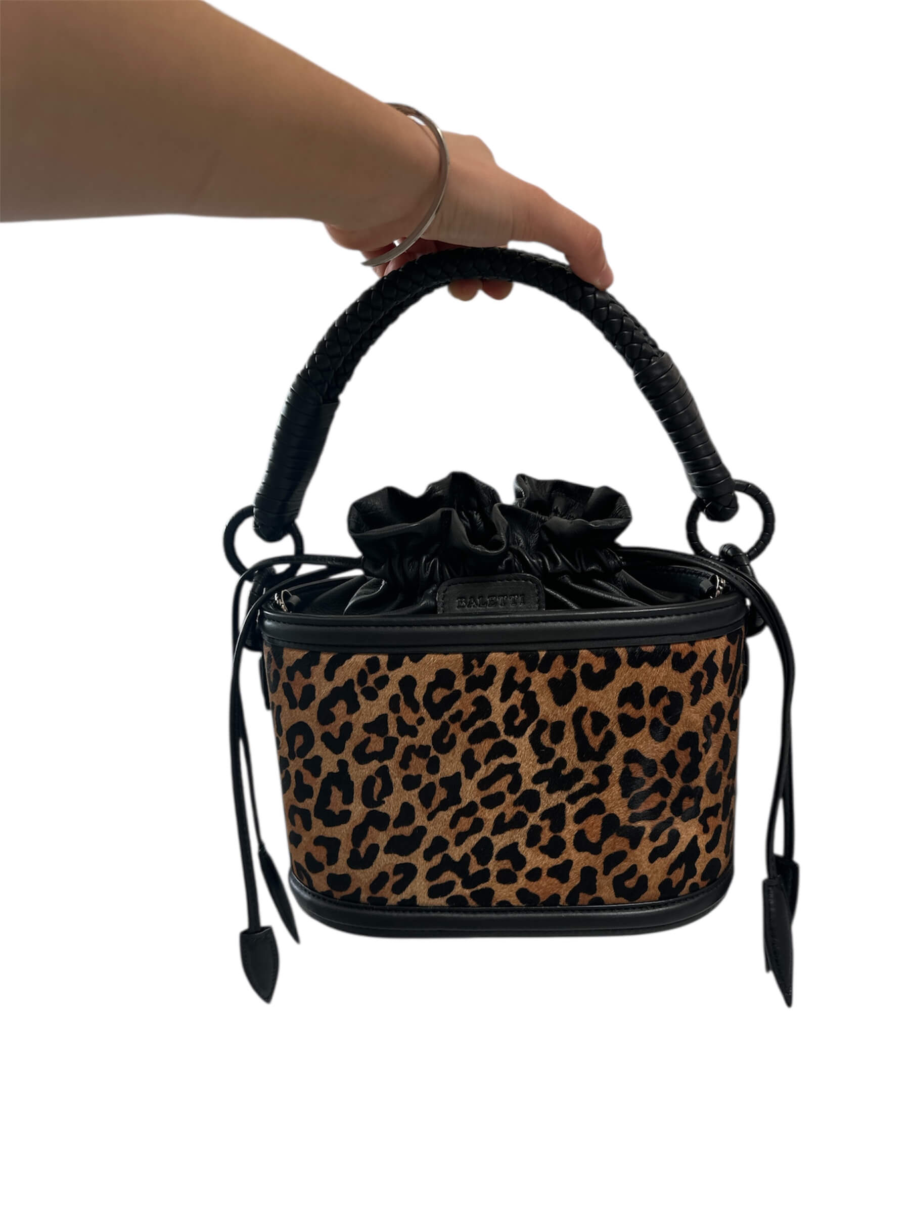 Leopard print handbag with black handle and strap on a white background.