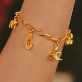 A close-up of a gold-plated charm bracelet on a person's wrist, featuring hand-painted charms.