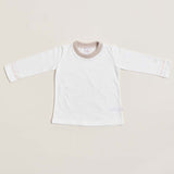 A long sleeve white baby shirt with beige pink detailing on the collar and cuffs, displayed against a neutral background.
