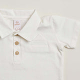A close-up of a white soft cotton polo shirt with a faux pocket, standing against a white background.
