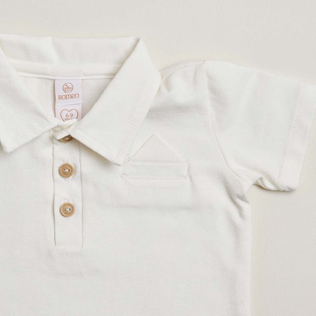A close-up of a white soft cotton polo shirt with a faux pocket, standing against a white background.