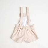 The back of overalls with bear embroidery on the front, standing against a white background.