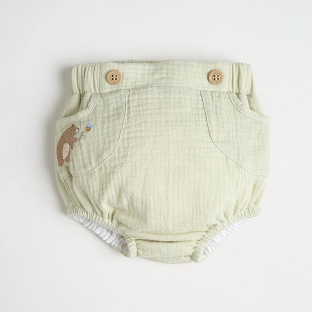A light green diaper cover with wooden button accents and a embroidered bear detail.