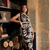 A photo of a woman wearing a floral black and white sari styled as a wrap dress, standing indoors.