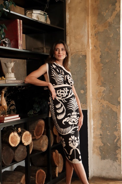 A photo of a woman wearing a floral black and white sari styled as a wrap dress, standing indoors.
