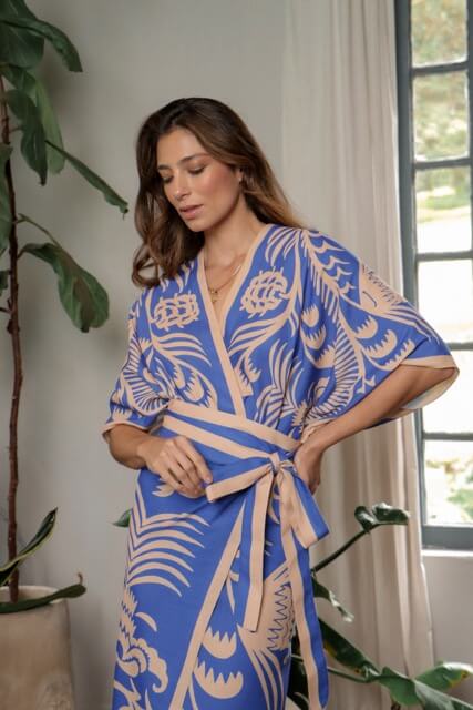 Woman wearing a blue and beige patterned kimono set indoors with plants around.