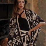 Woman wearing a black and white patterned kimono set against a rustic background.