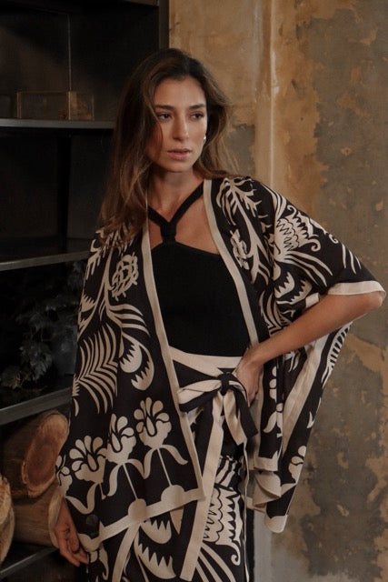 Woman wearing a black and white patterned kimono set against a rustic background.