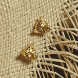 A close-up of gold-plated jaguar earring set, placed on a woven straw surface.