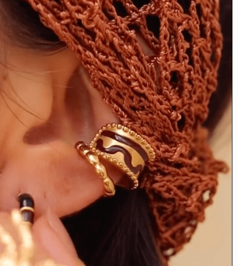 A close-up image of a woman's ear wearing a gold-plated ear cuffs.