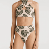 A a bikini with a halter top design and a shell print, featuring a crisscross design at the front and an adjustable tie at the back, with high waisted cheeky bikini bottoms, worn by a model.