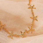 Gold starfish necklace on a beige fabric background.
