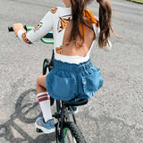 Child riding a bicycle on a paved road with grass and trees in the background